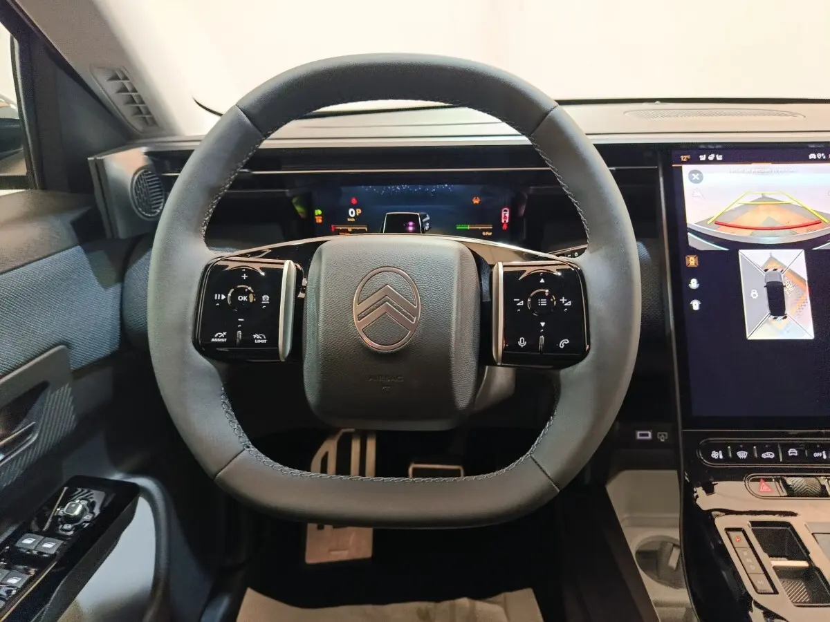 Vue intérieure centrée sur le volant cuir gris de la Citroën C5 Hybride 2026 avec écran tactile et affichage multifonctions.