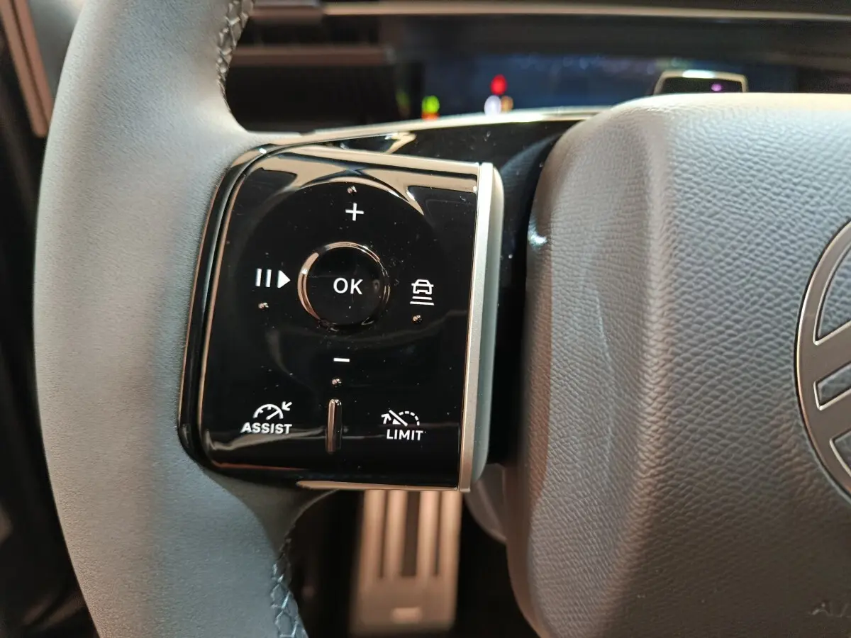 Gros plan sur la commande multifonctions gauche du volant cuir noir de la Citroën C5 Hybride 2026.