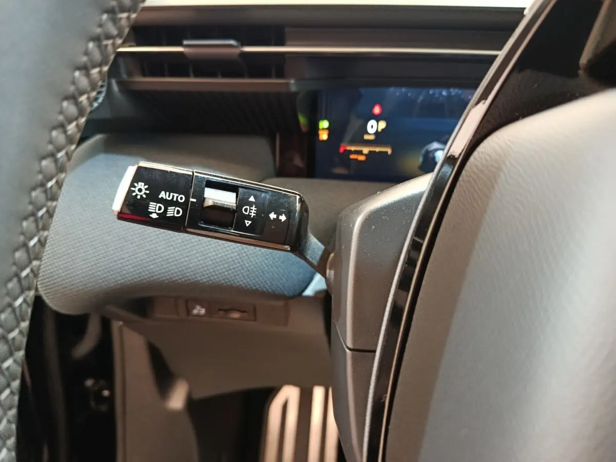 Gros plan sur la commande des phares et clignotants à gauche du volant dans l’habitacle noir du Citroën C5 Hybride 2026.