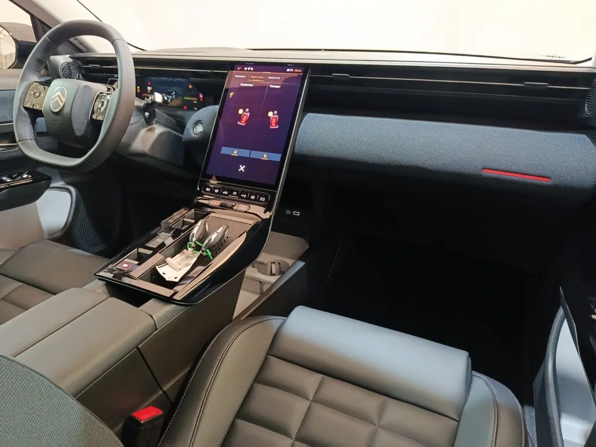 Vue intérieure côté passager de la Citroën C5 Hybride 2026, avec tableau de bord noir et écran tactile vertical central.