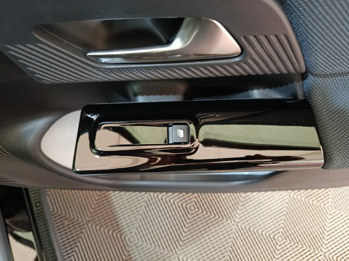 Gros plan sur la commande de lève-vitre noir brillant et la poignée intérieure côté conducteur d’une Citroën C5 Hybride.