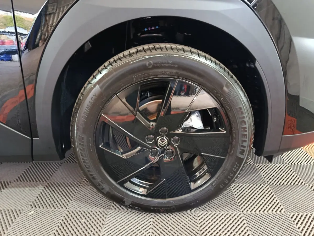 Gros plan sur la roue avant gauche noire avec jante en alliage noir brillant du Citroën C5 Hybride 2026.