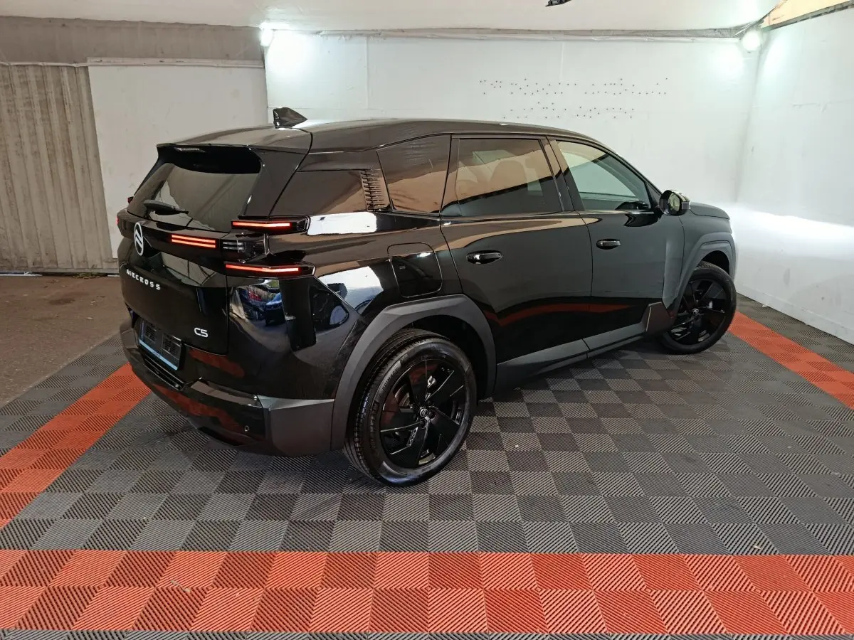 Vue 3/4 arrière droite d'un Citroën C5 noir brillant avec feux arrière LED horizontaux et jantes noires.
