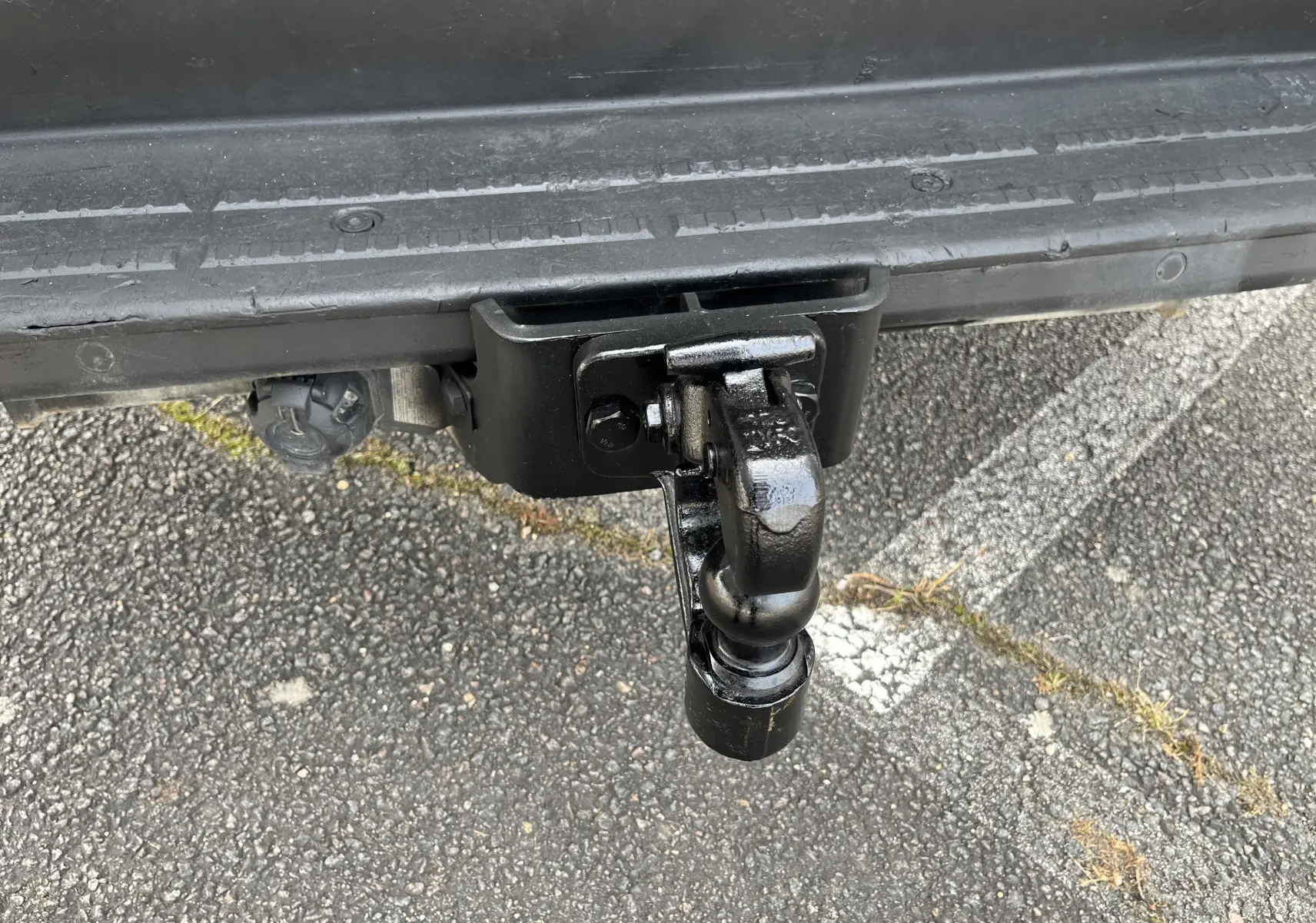 Gros plan sur l'attelage noir fixé à l'arrière du Volkswagen Crafter Fourgon blanc, avec prise électrique visible.