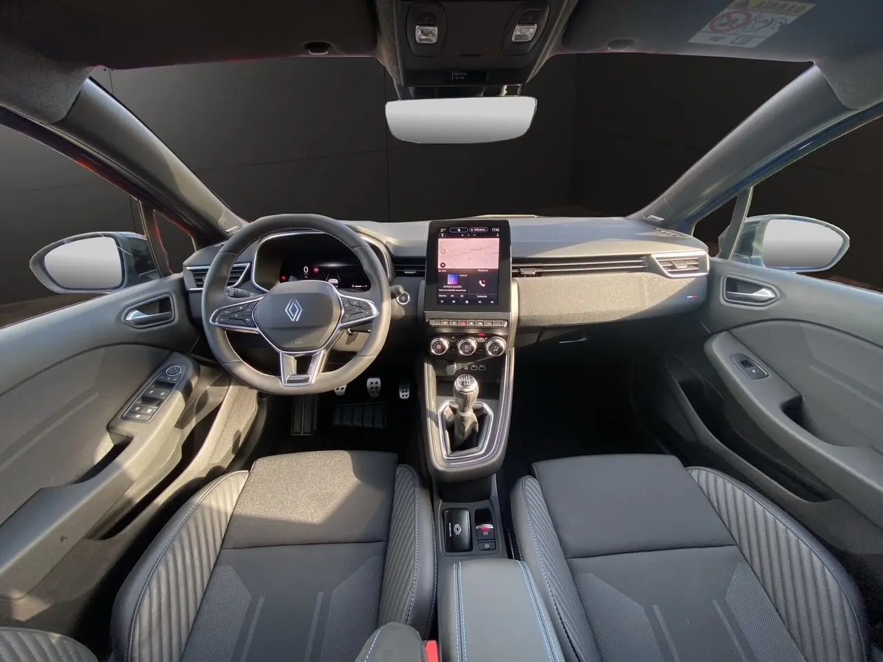 Vue intérieure avant de la Renault Clio V TCE 90 Esprit Alpine 2025, sièges noirs et tableau de bord moderne avec écran tactile.