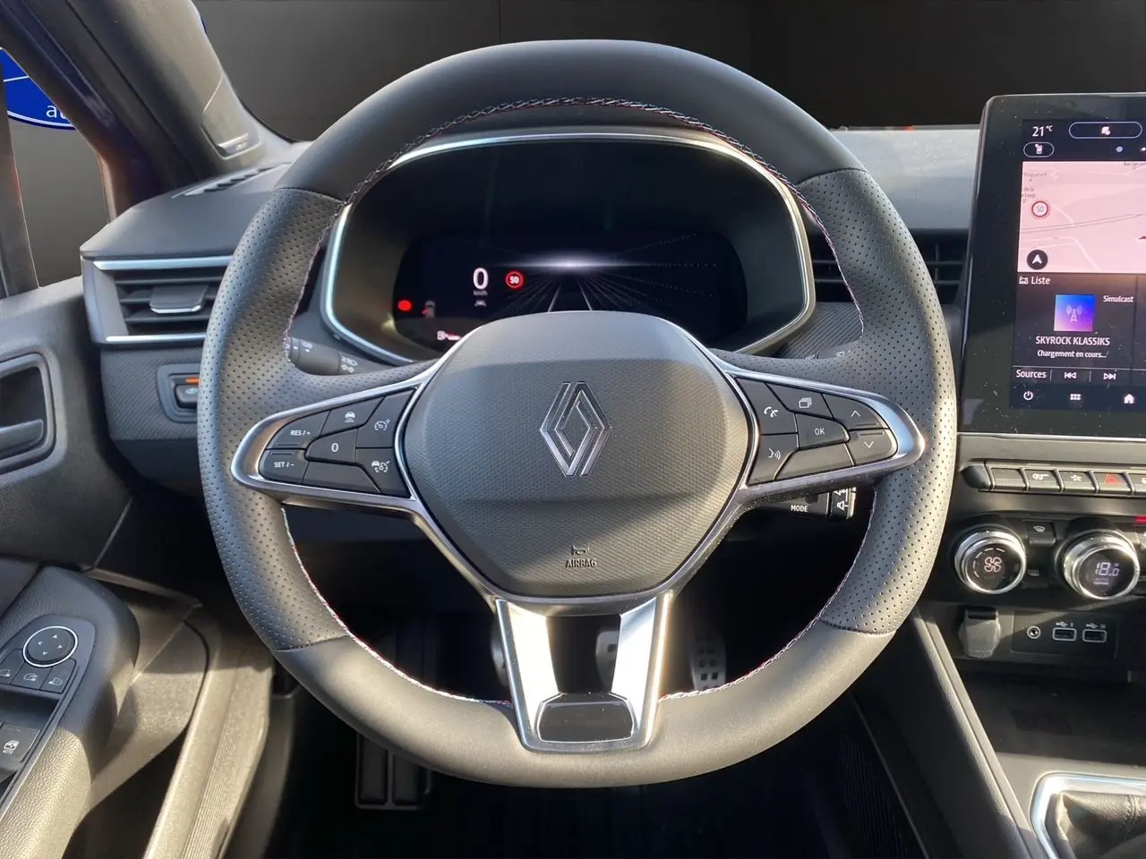Vue centrée sur le volant perforé noir de la Renault Clio V TCE 90 Esprit Alpine avec tableau de bord numérique et écran tactile.