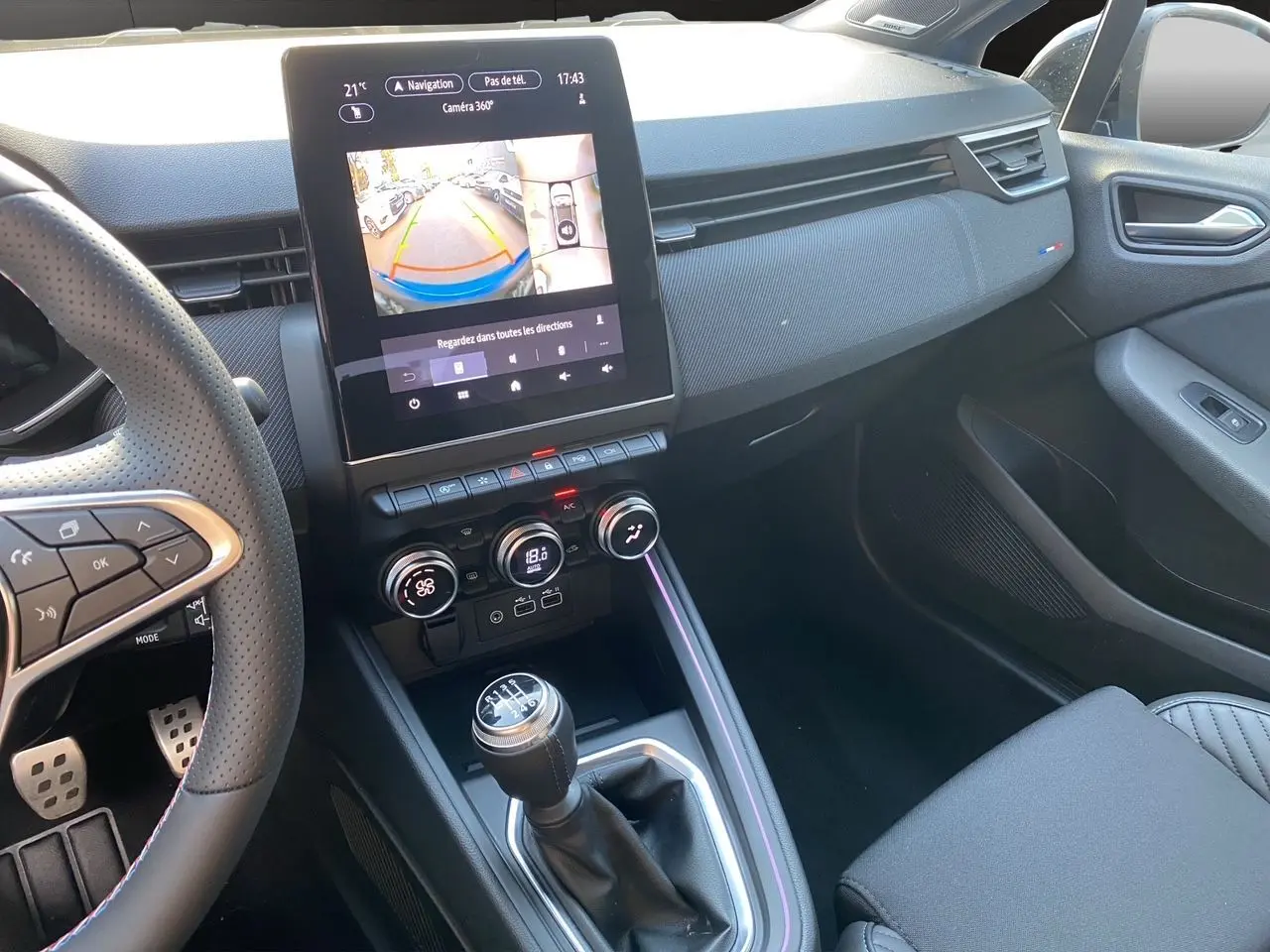 Vue intérieure côté passager de la Renault Clio V TCE 90 Esprit Alpine 2025, avec écran tactile et levier de vitesse manuel.