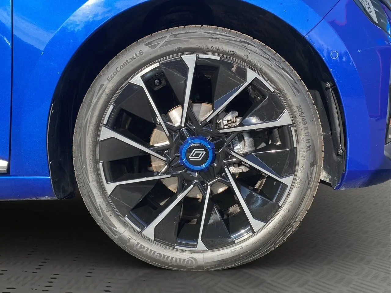 Gros plan sur la roue avant droite de la Renault Clio V TCE 90 Esprit Alpine bleu Iron avec jante noire et argentée.