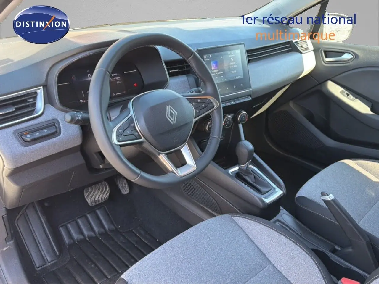 Intérieur avant droit de Renault Clio 2025, volant cuir multifonction, écran tactile et sellerie tissu gris.