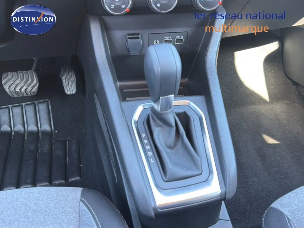 Gros plan sur la console centrale de la Renault Clio blanche 2025, montrant le levier de vitesse automatique et les pédales.