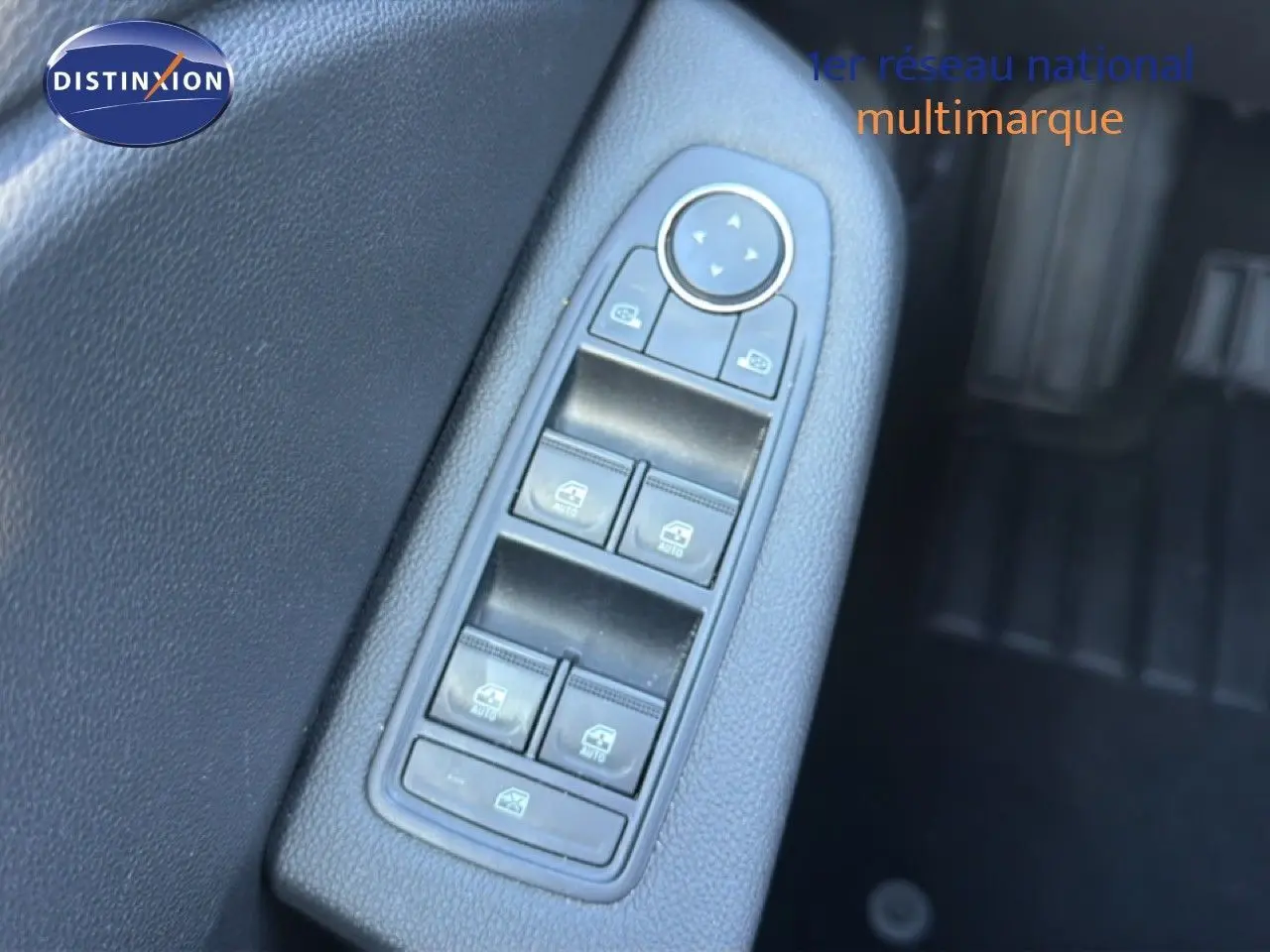 Gros plan sur la commande des vitres électriques côté conducteur d’une Renault Clio blanche, intérieur noir.