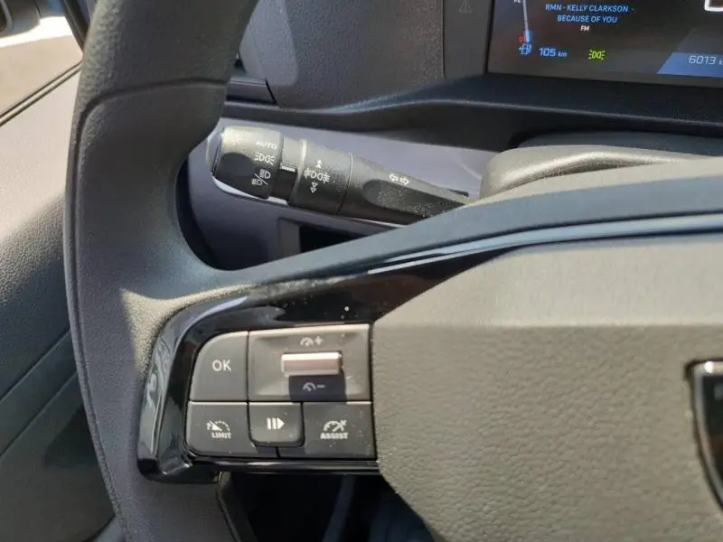 Gros plan sur les commandes au volant du Peugeot Expert Fourgon blanc 2025, avec affichage numérique partiel en arrière-plan.