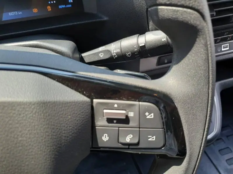 Gros plan sur les commandes audio au volant du Peugeot Expert Fourgon blanc, avec levier d'essuie-glace en arrière-plan.