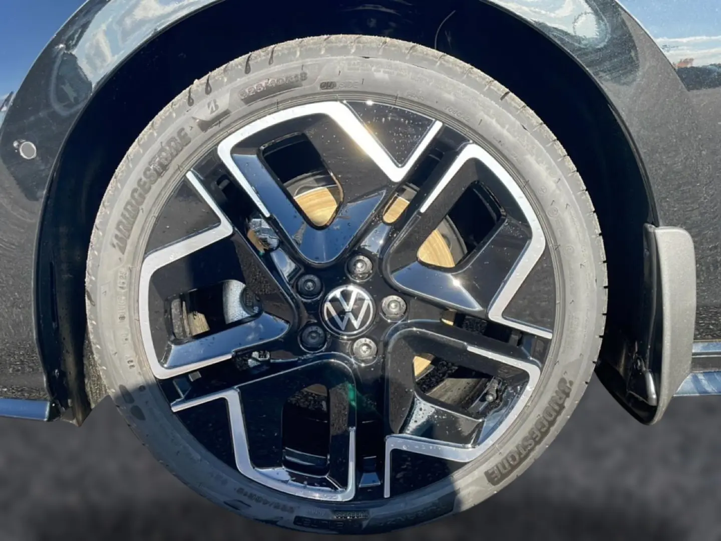 Gros plan sur la roue avant droite noire d’une Volkswagen Golf 2026 avec jante alliage R-Line brillante.
