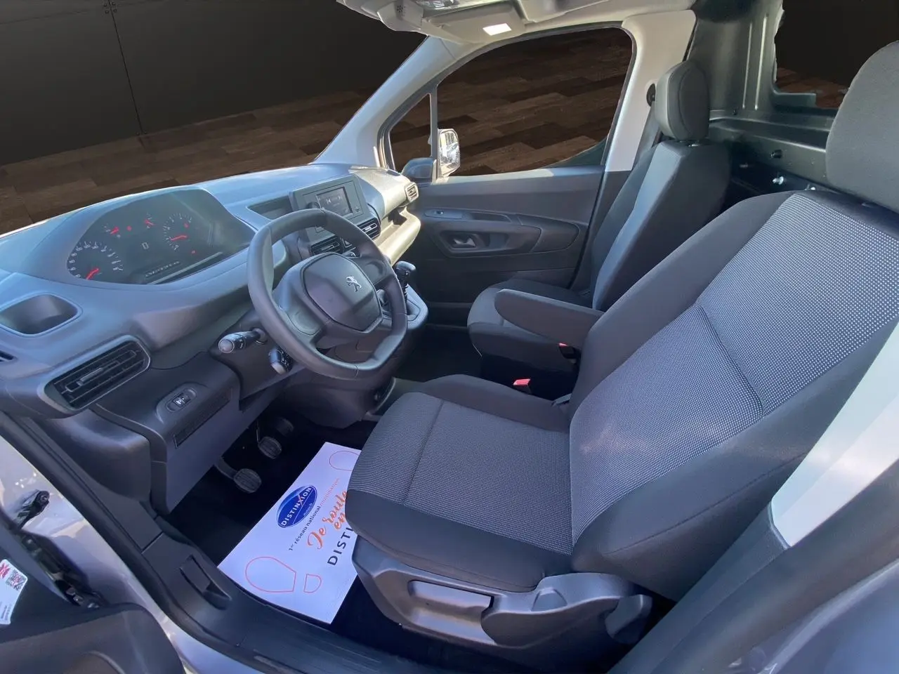 Vue intérieure côté conducteur du Peugeot Partner Fourgon Dangel 4x4 2025, sièges tissu noir et tableau de bord moderne.