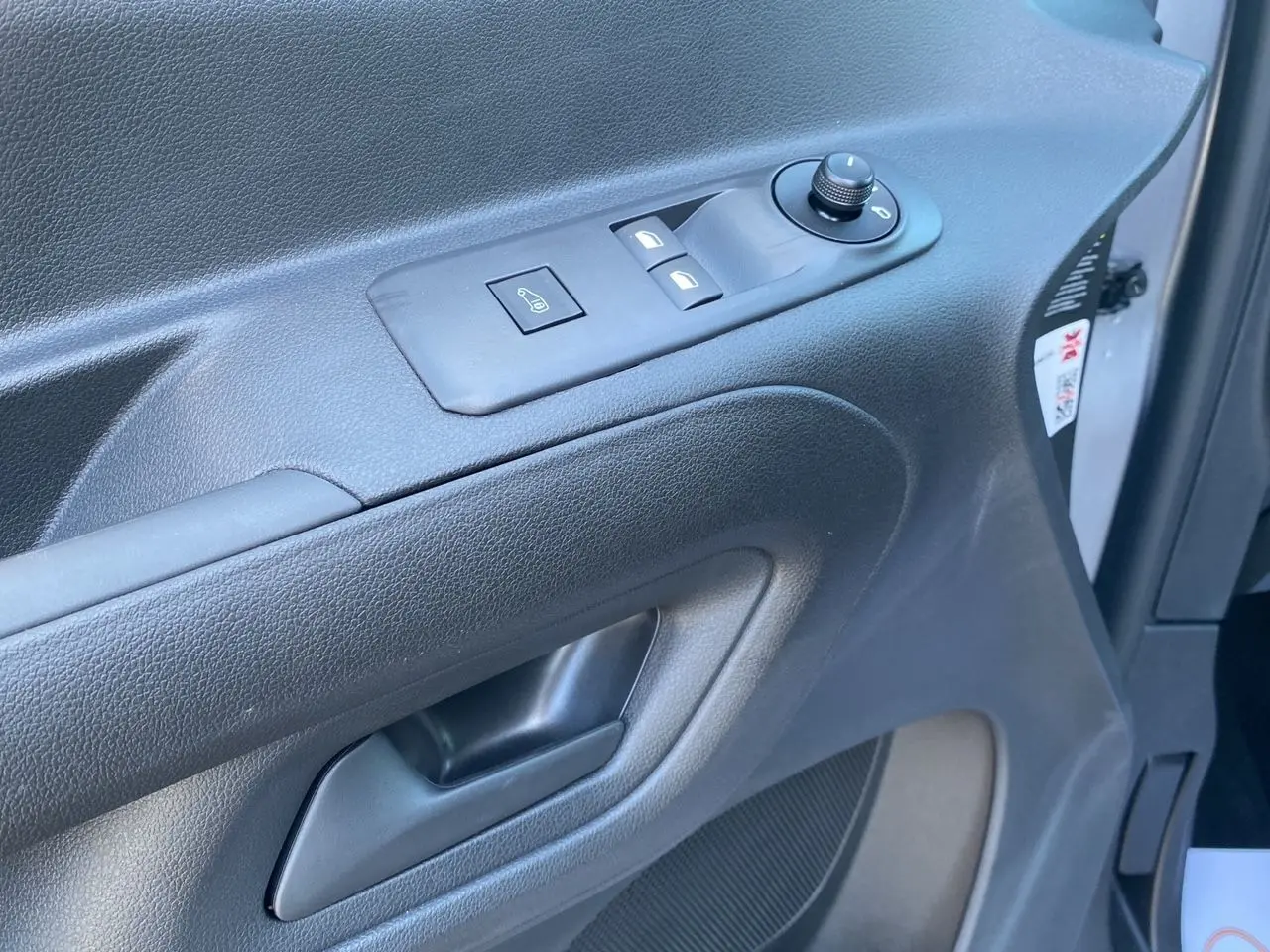 Gros plan sur la porte intérieure côté gauche du Peugeot Partner Fourgon Dangel 4x4 gris Artense, avec commandes électriques.