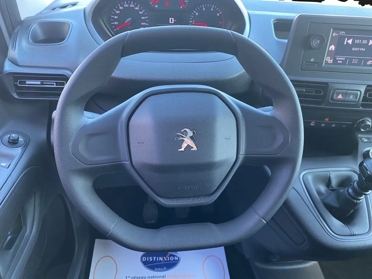 Vue rapprochée du volant Peugeot noir et du tableau de bord avec levier de vitesses manuel du Partner Fourgon 2025.