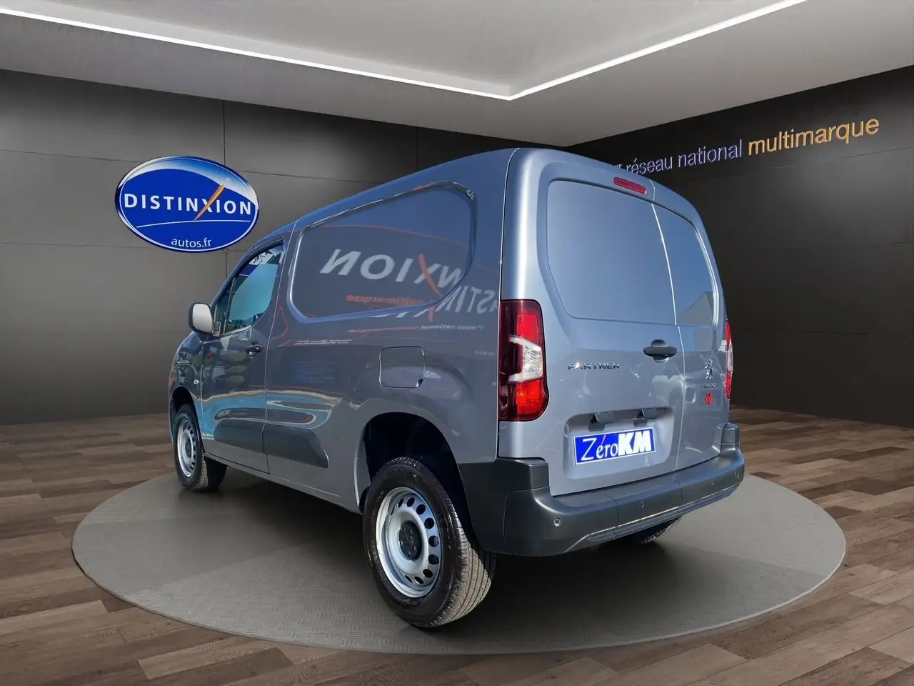 Peugeot Partner Fourgon gris Artense métal vu en 3/4 arrière droit avec portes arrière fermées dans un showroom.