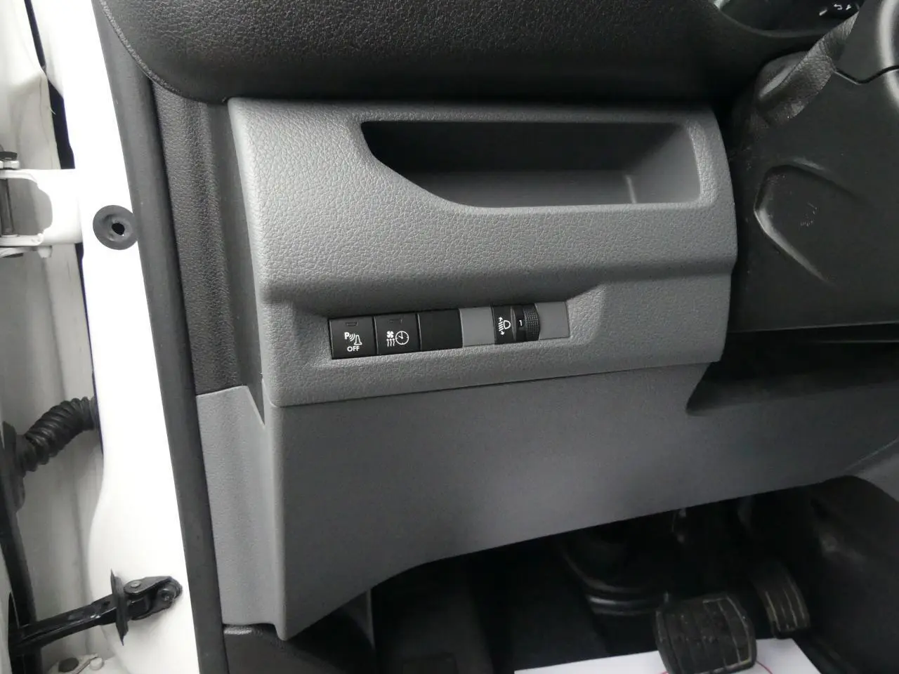 Détail des commandes sous le tableau de bord côté gauche du Peugeot Expert Fourgon blanc 2019.