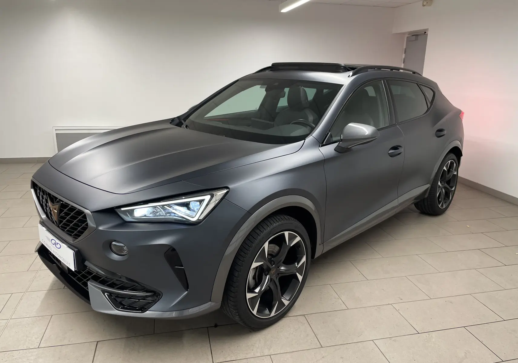 Vue 3/4 avant droite du CUPRA Formentor 1.5 TSI 150 DSG7 en gris magnétique mat avec jantes sport et toit ouvrant.