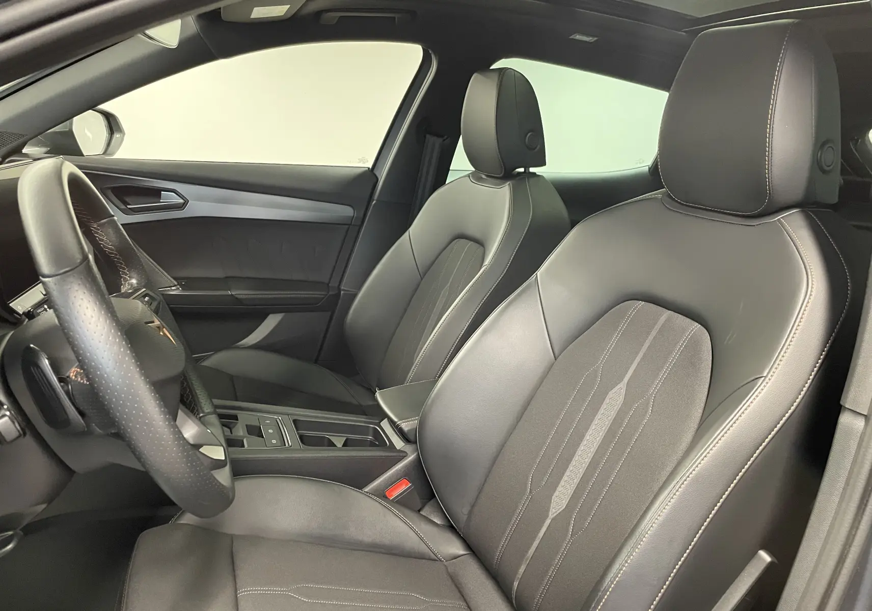 Vue intérieure côté conducteur du CUPRA Formentor 1.5 TSI 150 DSG7 avec sièges cuir noir et surpiqûres contrastées.