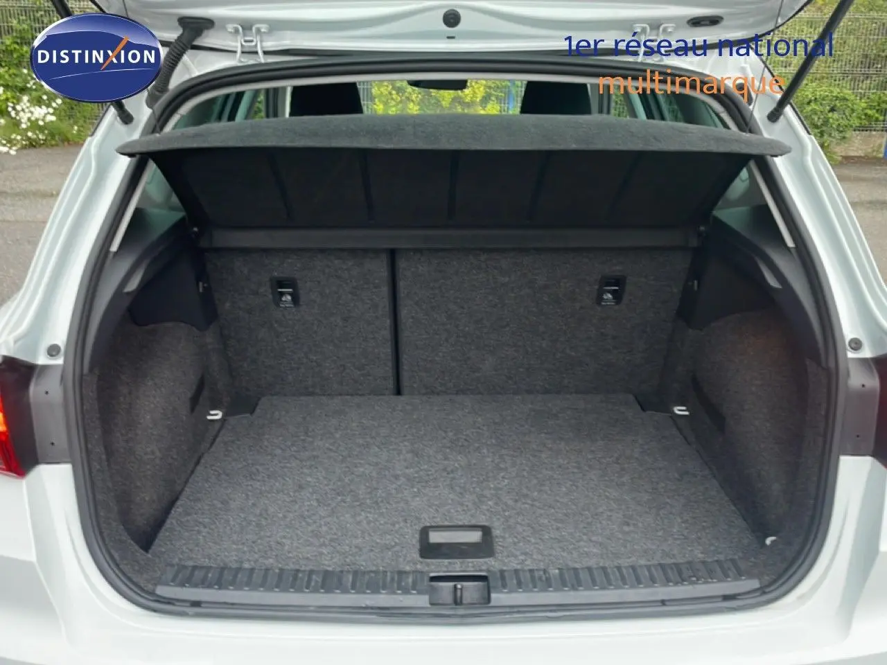 Coffre ouvert vu de l'arrière d'un SEAT Arona blanc alpin métal avec toit noir, montrant un espace de chargement vide et propre.