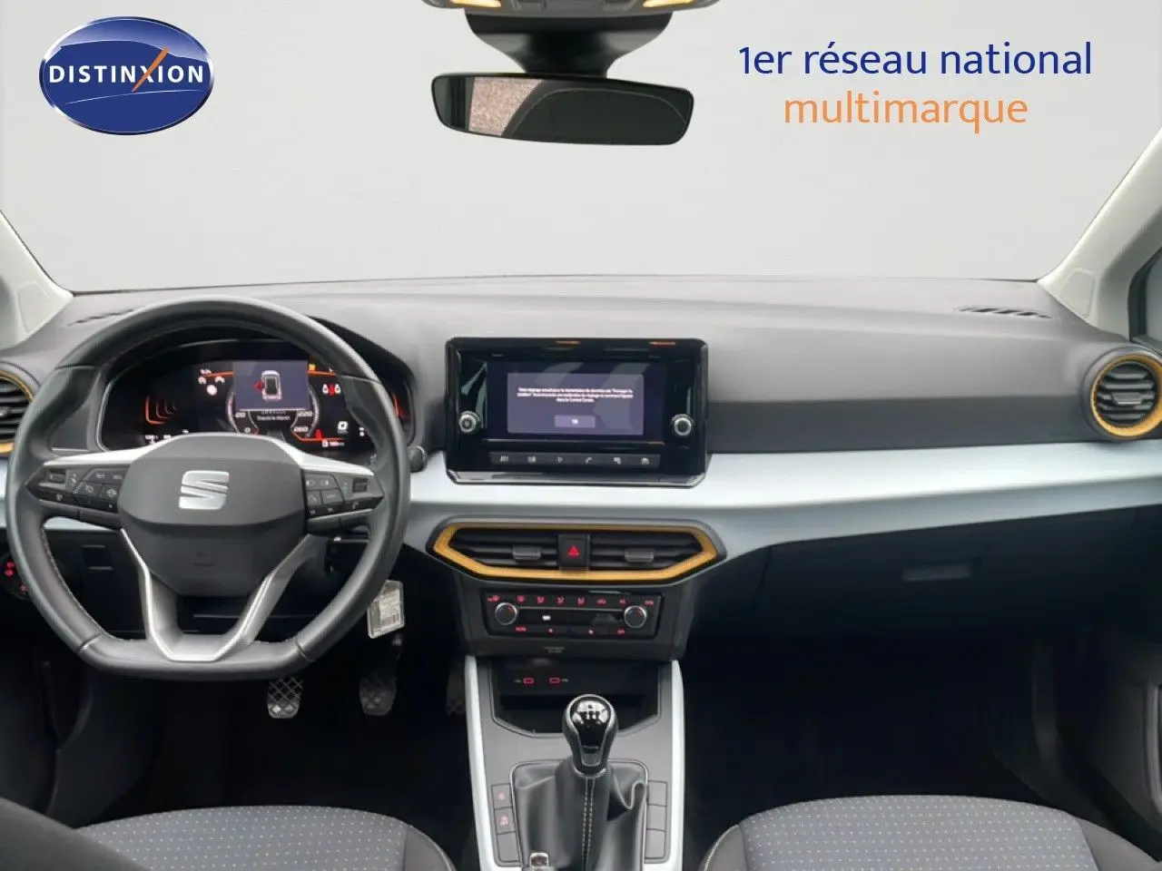 Vue intérieure avant du tableau de bord du SEAT Arona blanc alpin avec volant cuir multifonction et écran tactile central.
