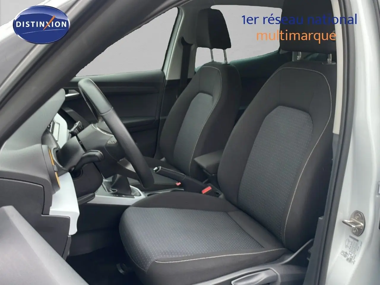 Vue intérieure côté conducteur du SEAT Arona blanc alpin avec sièges tissu noir et volant cuir.