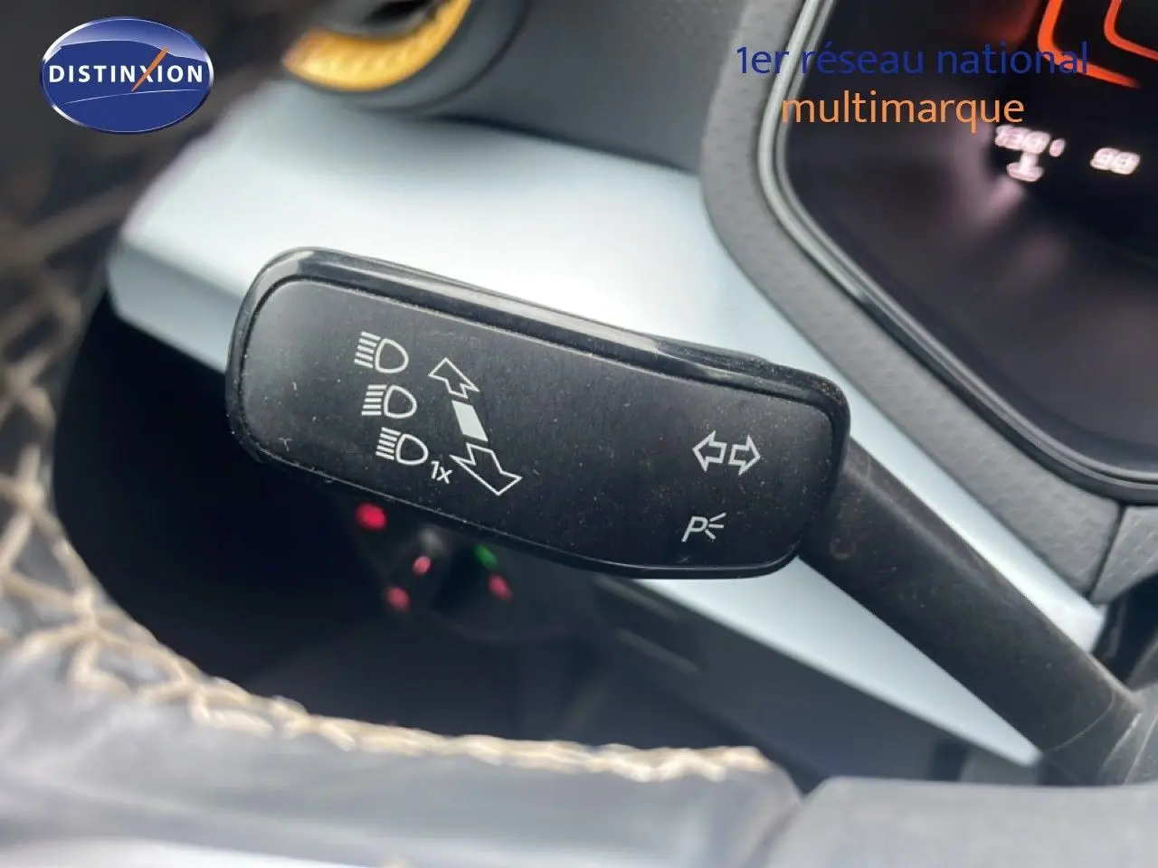 Gros plan sur la manette de clignotants noire à gauche du volant dans l’habitacle du SEAT Arona blanc alpin métal avec toit noir.