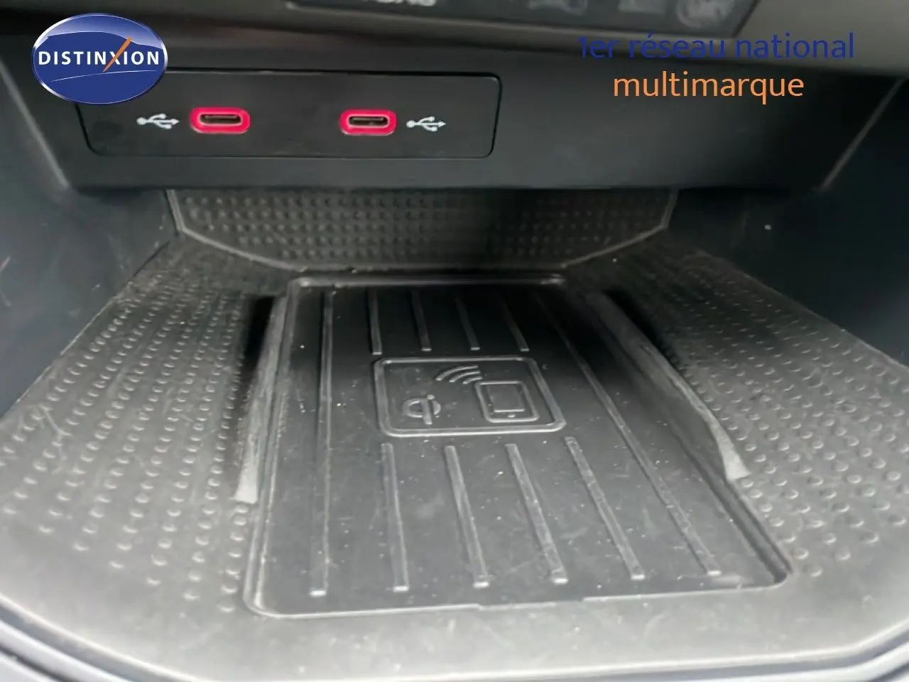 Gros plan sur la zone de recharge sans fil et deux ports USB rouges dans l'habitacle du SEAT Arona blanc toit noir.