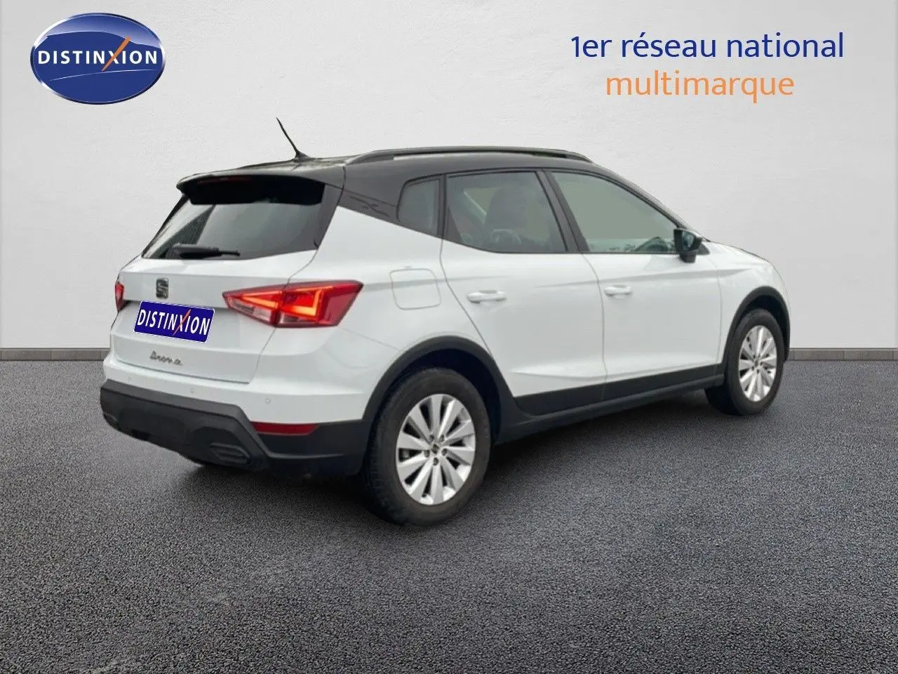 Vue 3/4 arrière droite d'un SEAT Arona blanc alpin avec toit noir, sur fond neutre en extérieur.