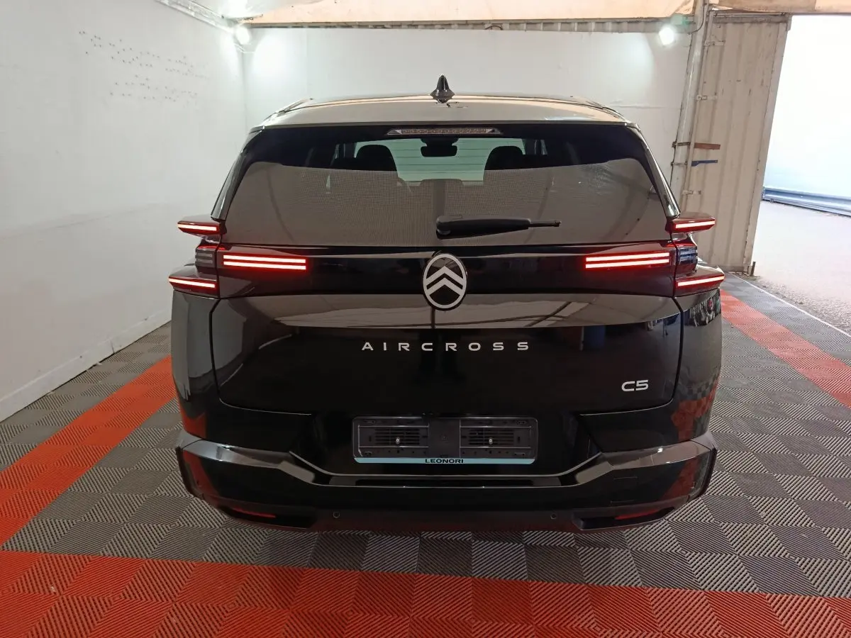 Vue arrière d'une Citroën C5 Aircross noire avec feux arrière LED allumés dans un garage.