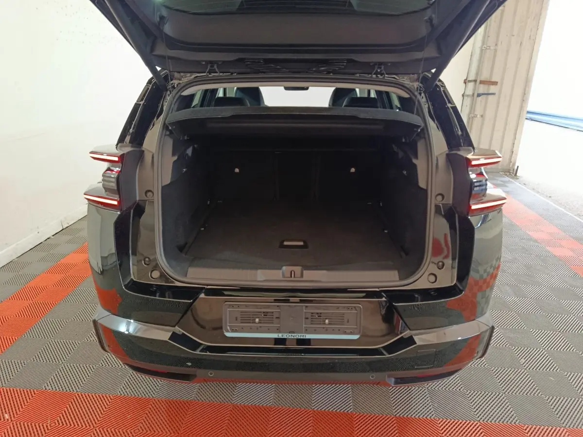 Vue arrière d'une Citroën C5 Hybride noire avec coffre ouvert et feux arrière LED allumés.