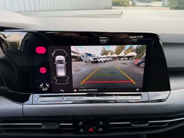 Intérieur côté conducteur d'une Volkswagen Golf VIII gris dauphin, tableau de bord numérique et volant multifonction visible.