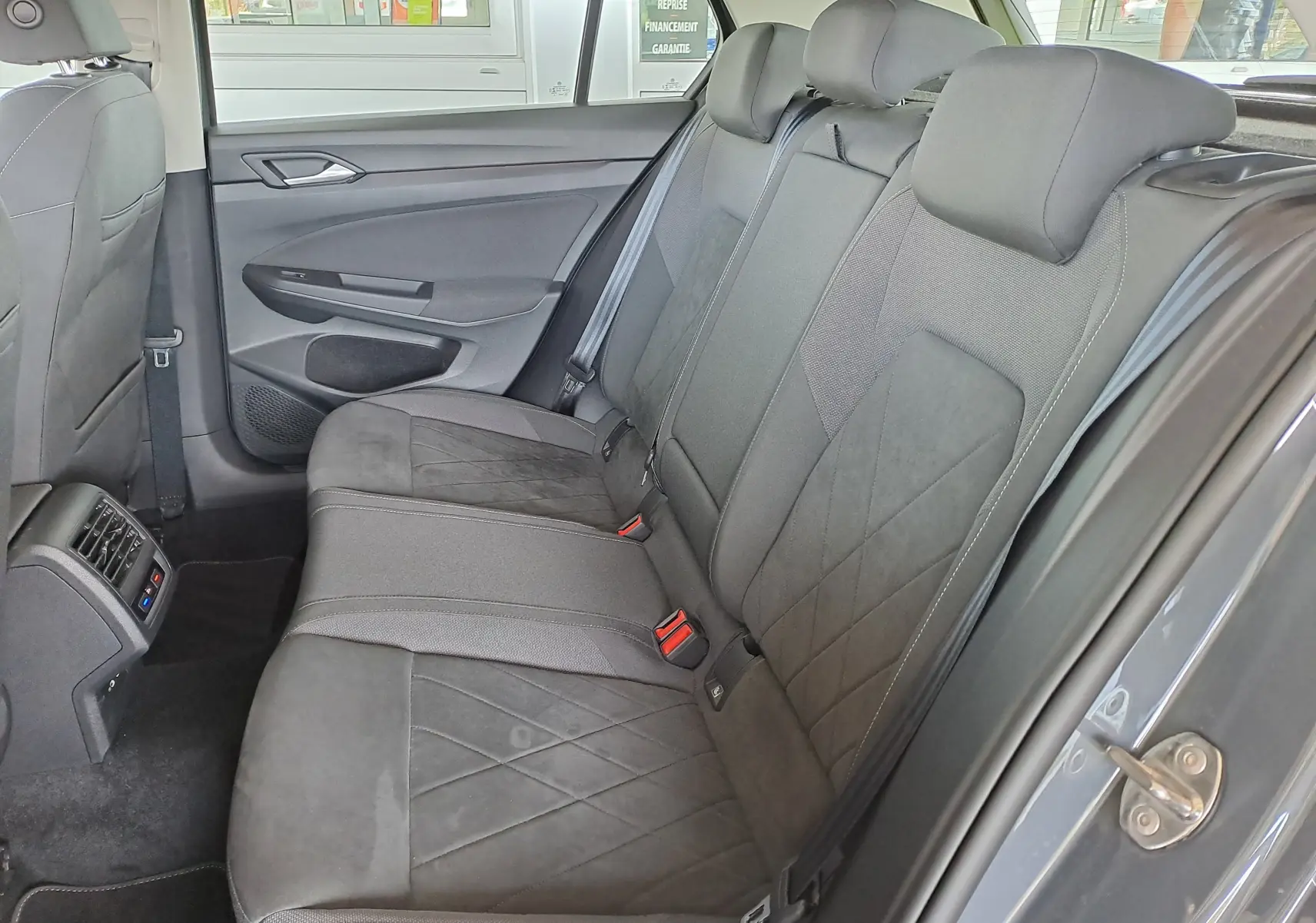 Coffre ouvert d'une Volkswagen Golf VIII gris dauphin, vue arrière, avec câble de recharge hybride visible à l'intérieur.