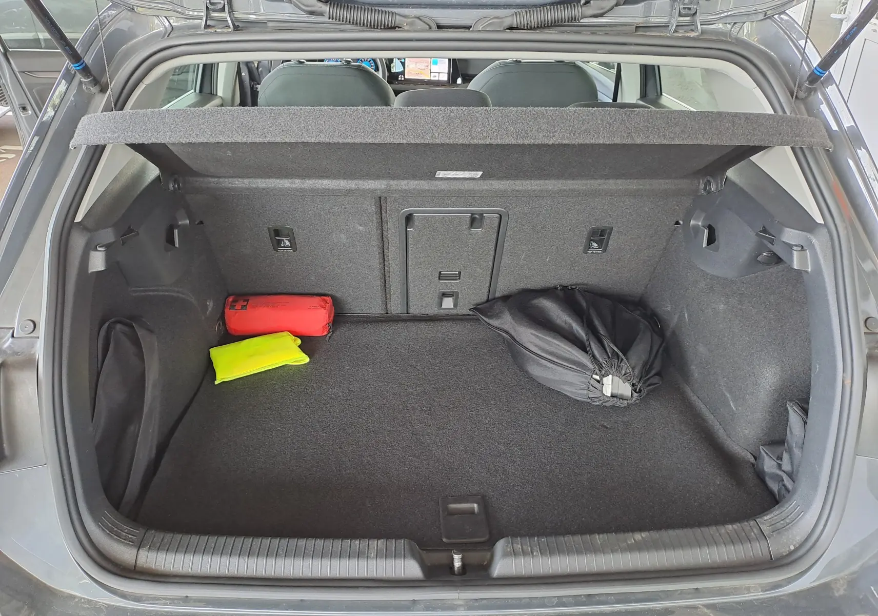 Gros plan sur la console centrale noire de la Volkswagen Golf VIII hybride, montrant les boutons start/stop et parking.