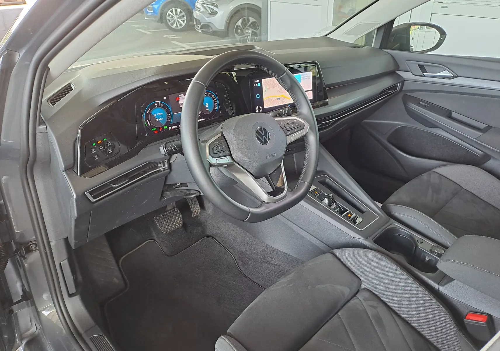 Intérieur côté conducteur de la Volkswagen Golf VIII gris dauphin, tableau de bord digital et volant multifonction moderne.