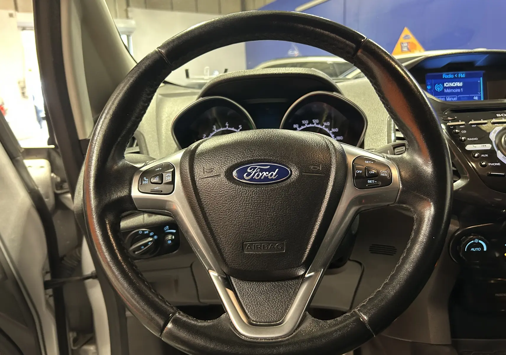 Volant en cuir noir de Ford EcoSport Titanium 2018, vue frontale centrée sur les commandes au volant et tableau de bord.