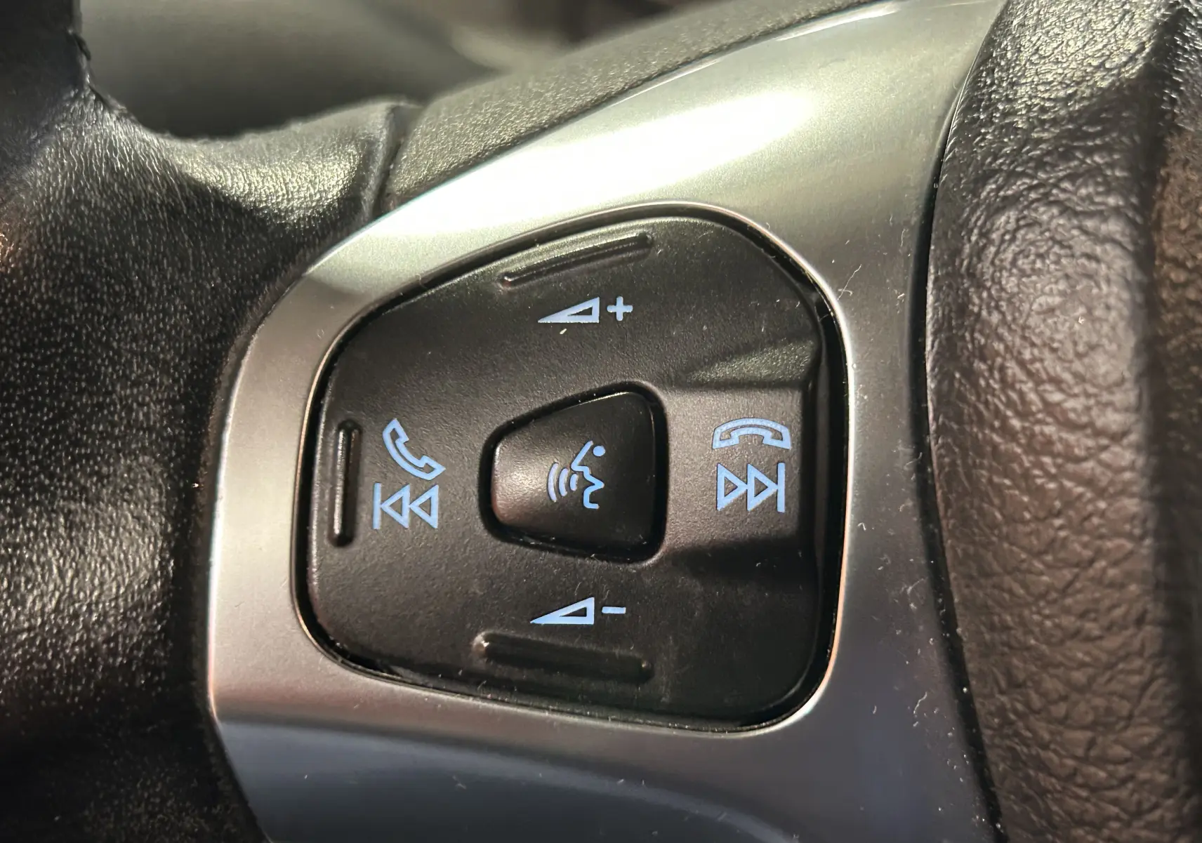 Gros plan sur les commandes vocales et audio au volant en cuir noir du Ford EcoSport gris Titanium 2018.