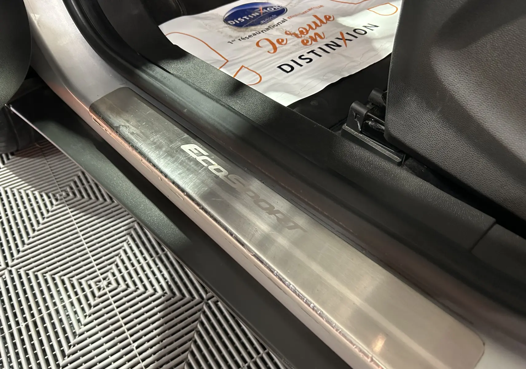 Gros plan sur la plaque de seuil de porte avant gauche du Ford EcoSport gris, mettant en valeur le logo EcoSport.