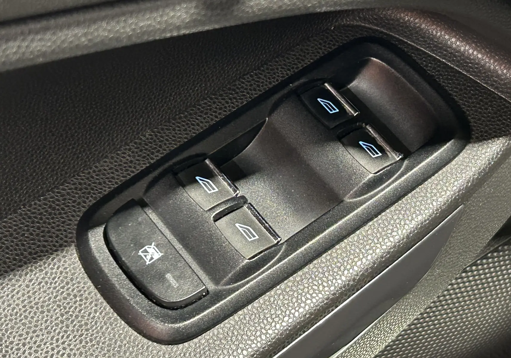 Gros plan sur les commandes de lève-vitres électriques noires côté conducteur du Ford EcoSport gris 2018.