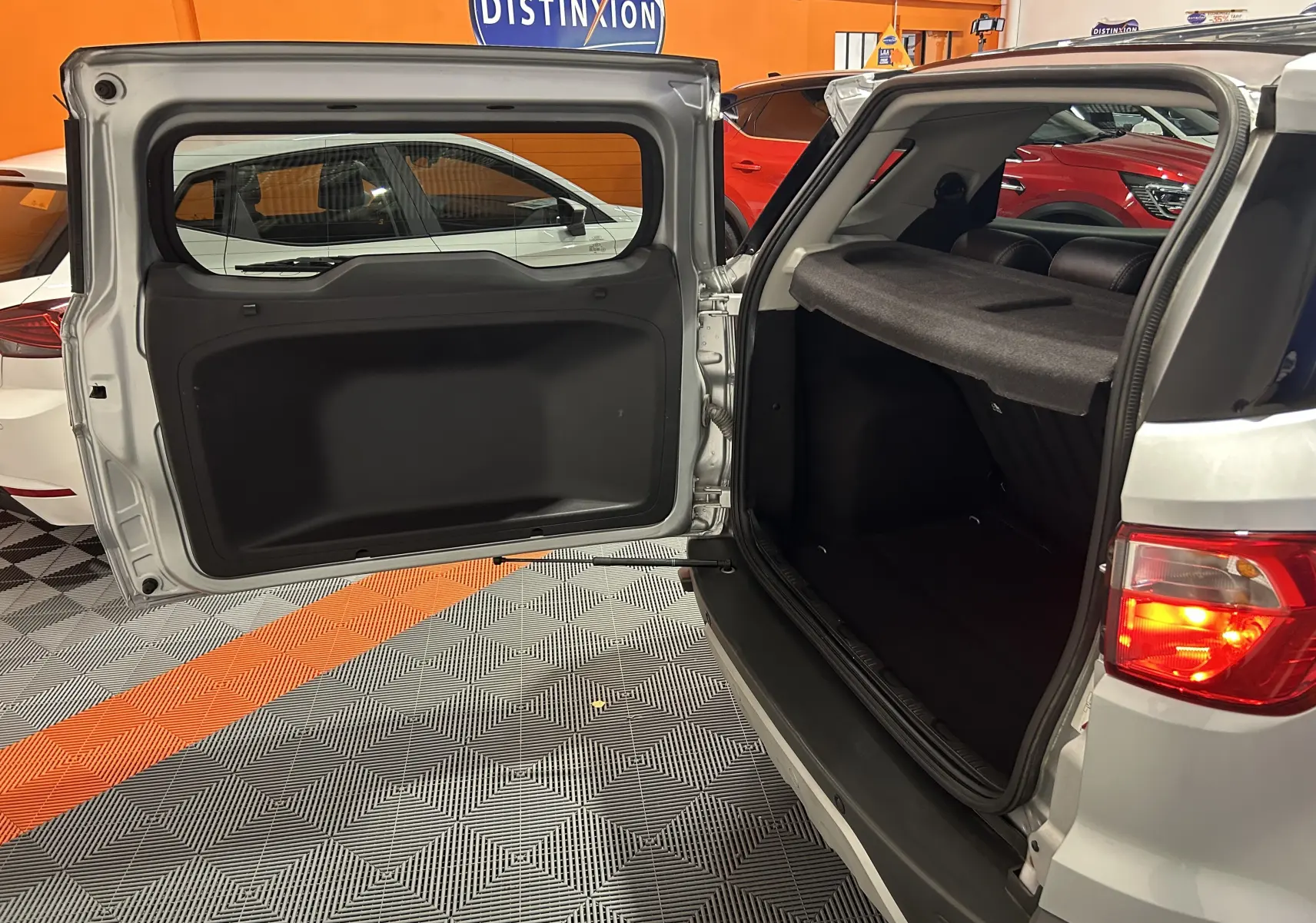 Vue arrière ouverte du Ford EcoSport gris 2018 montrant le coffre et la porte battante avec feu arrière allumé.