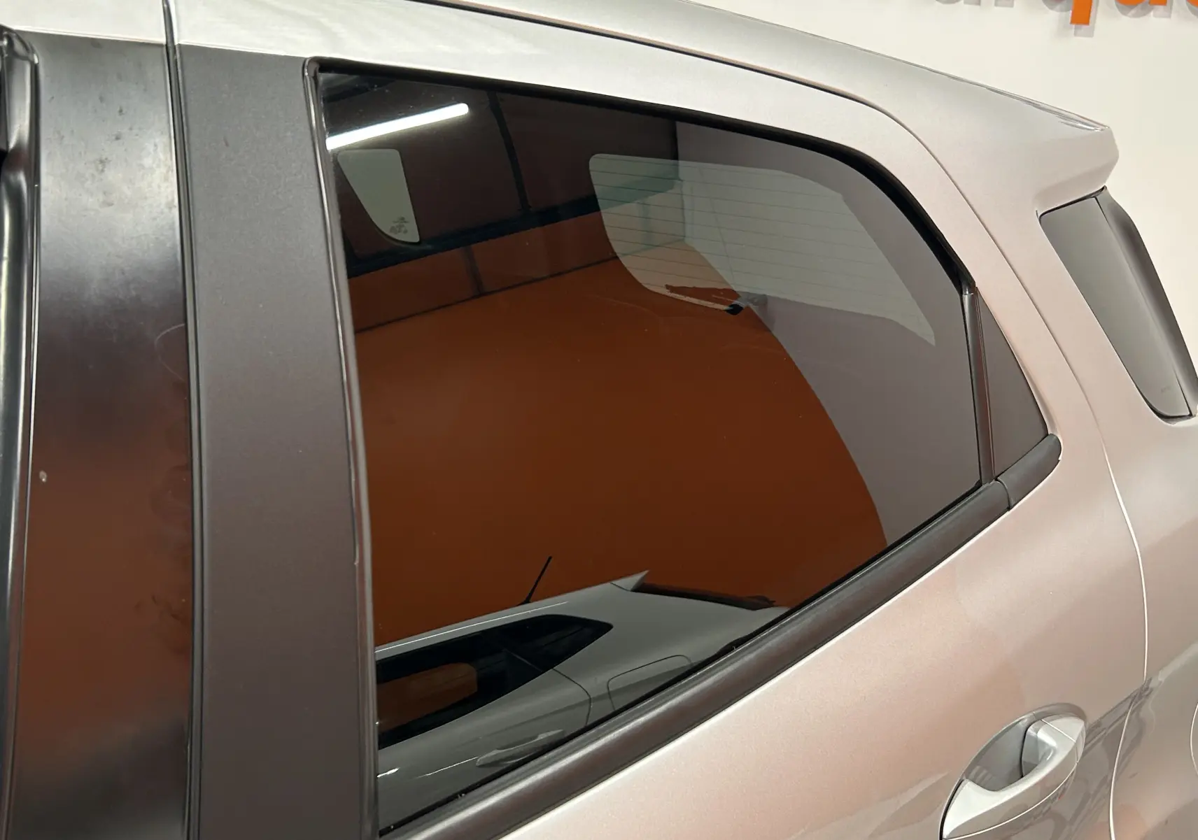 Détail de la porte arrière côté droit d'un Ford EcoSport gris 2018 avec vitre teintée et poignée chromée.