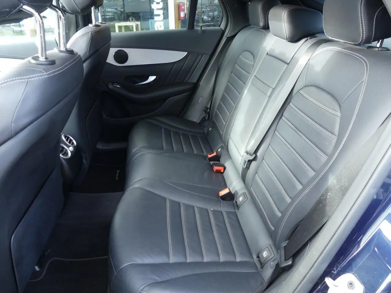 Vue intérieure des sièges arrière en cuir noir du Mercedes GLC Coupé 300 hybride bleu foncé, avec surpiqûres contrastées.