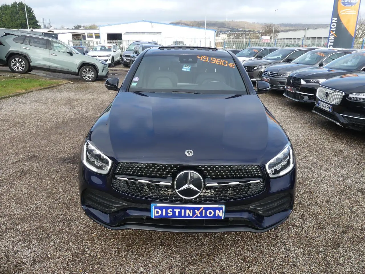 Vue avant d'un Mercedes GLC Coupé bleu foncé avec calandre AMG et logo étoile bien visible sur un parking.