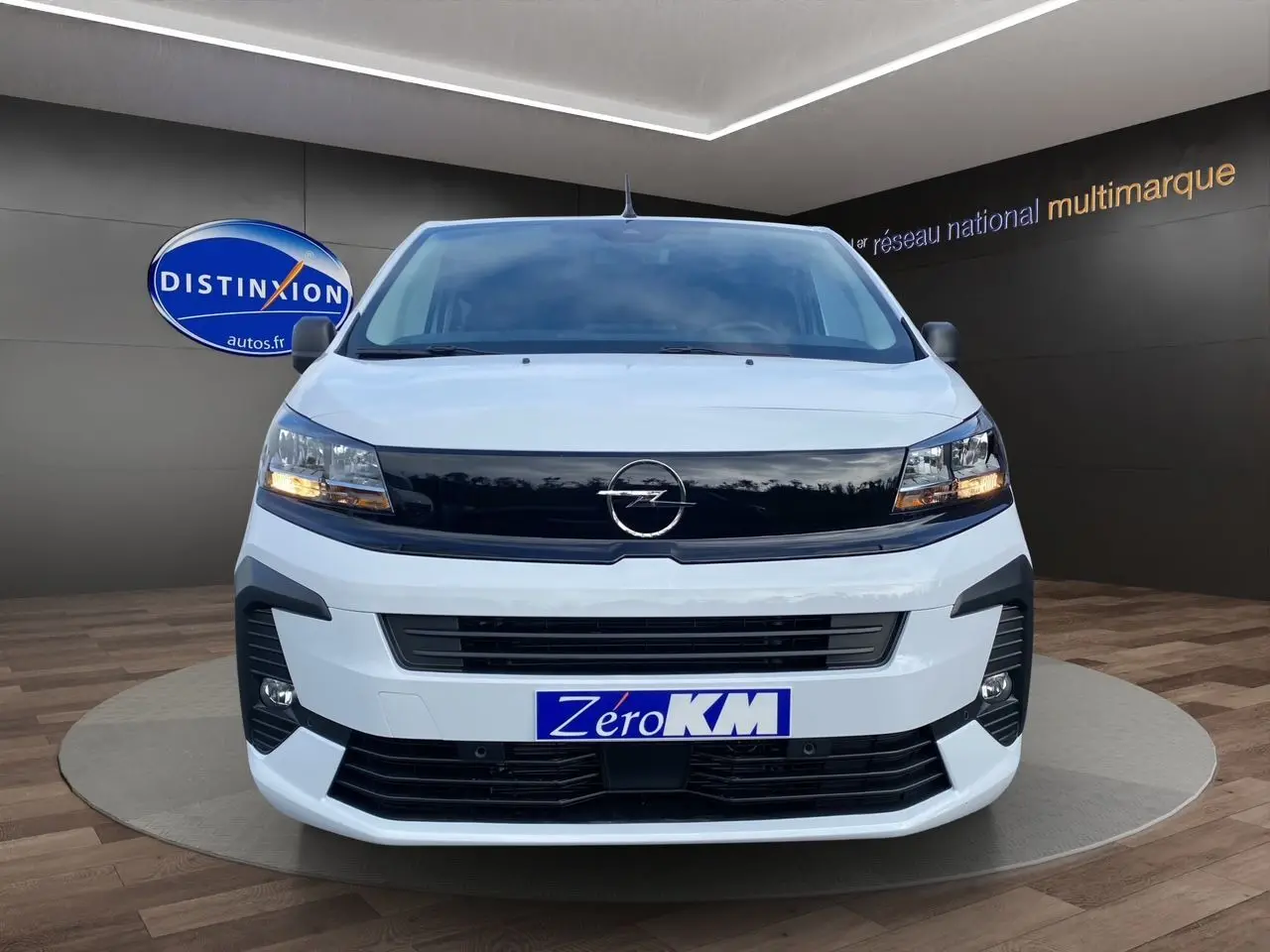 Vue frontale d'un Opel Vivaro blanc avec calandre noire et feux allumés en showroom.