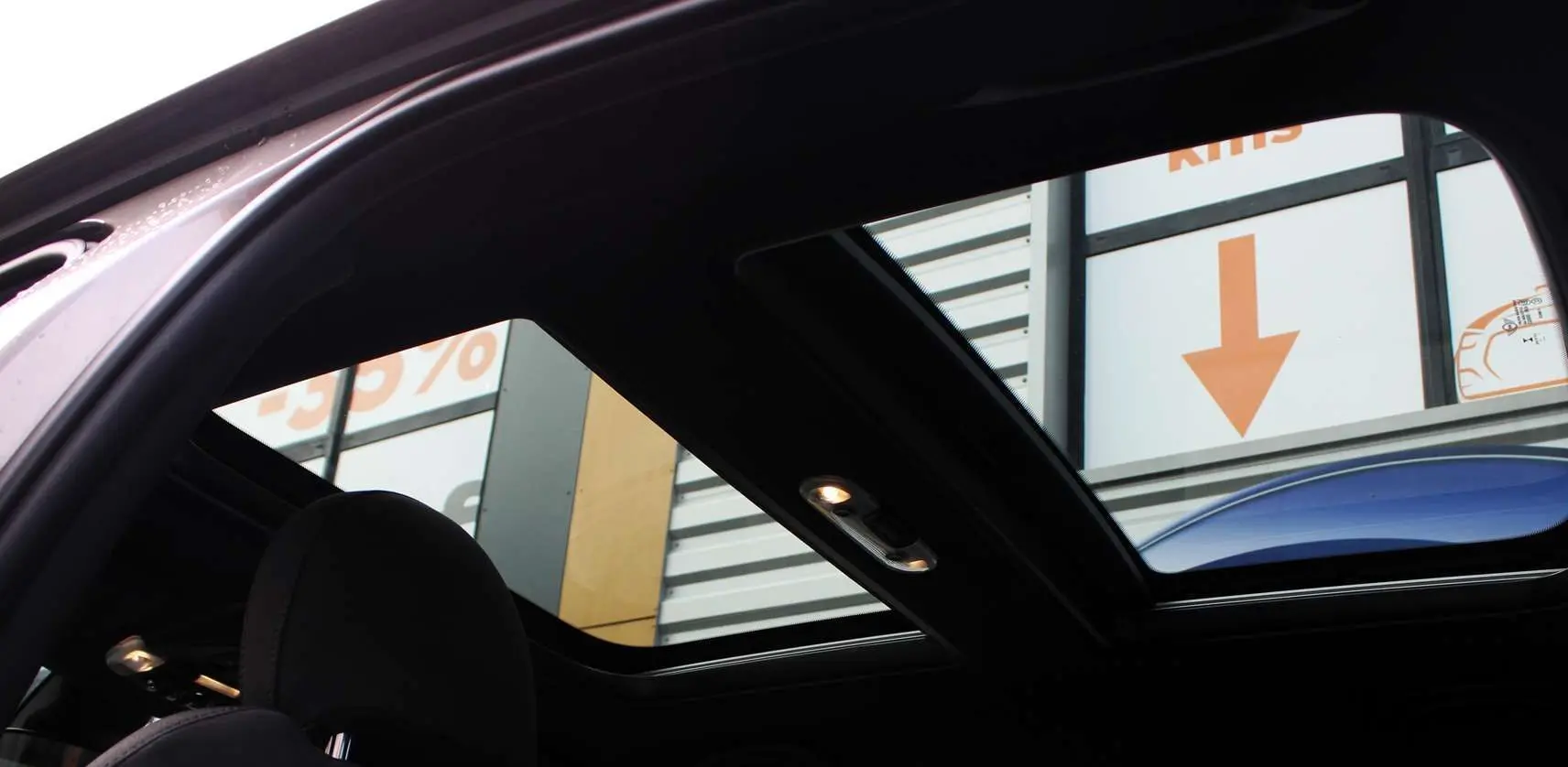 Toit panoramique ouvert montrant l'intérieur noir d'un MINI Countryman hybride Melting Silver avec toit noir.