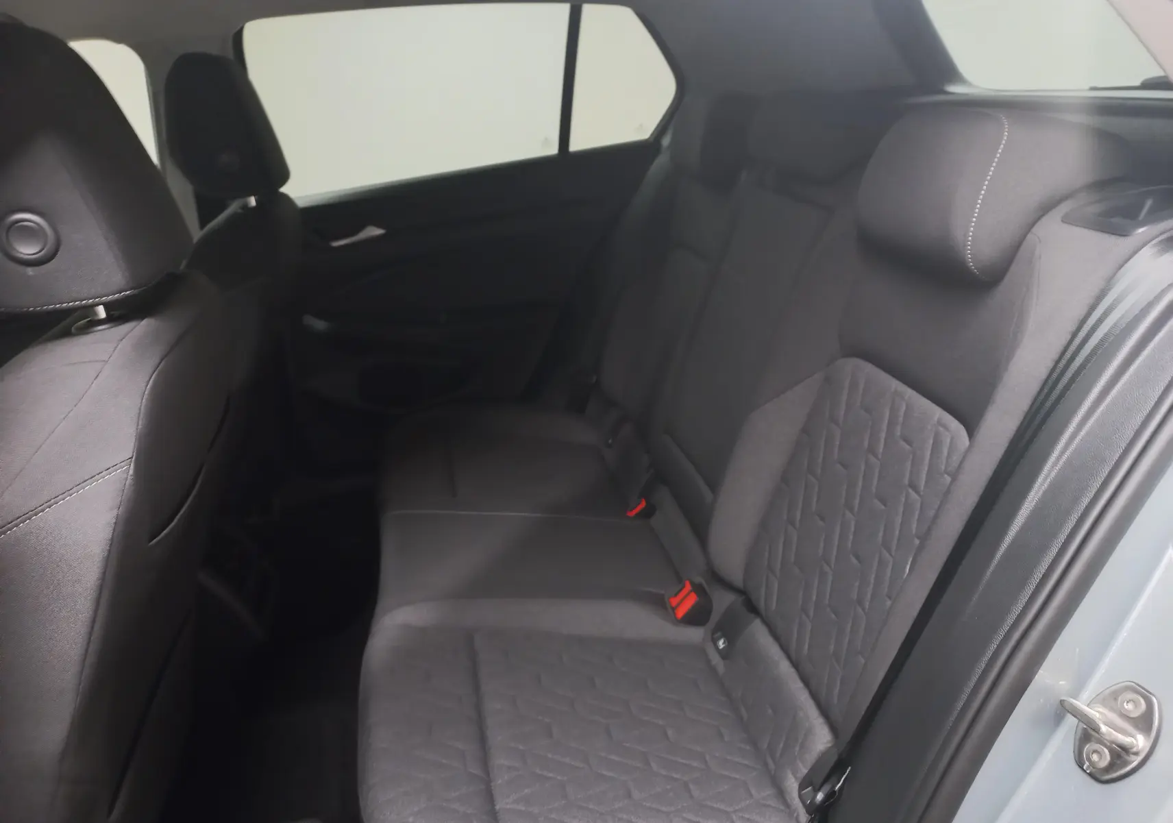 Vue intérieure des sièges arrière en tissu gris foncé de la Volkswagen Golf 1.5 eHybrid 2025, porte ouverte côté droit.
