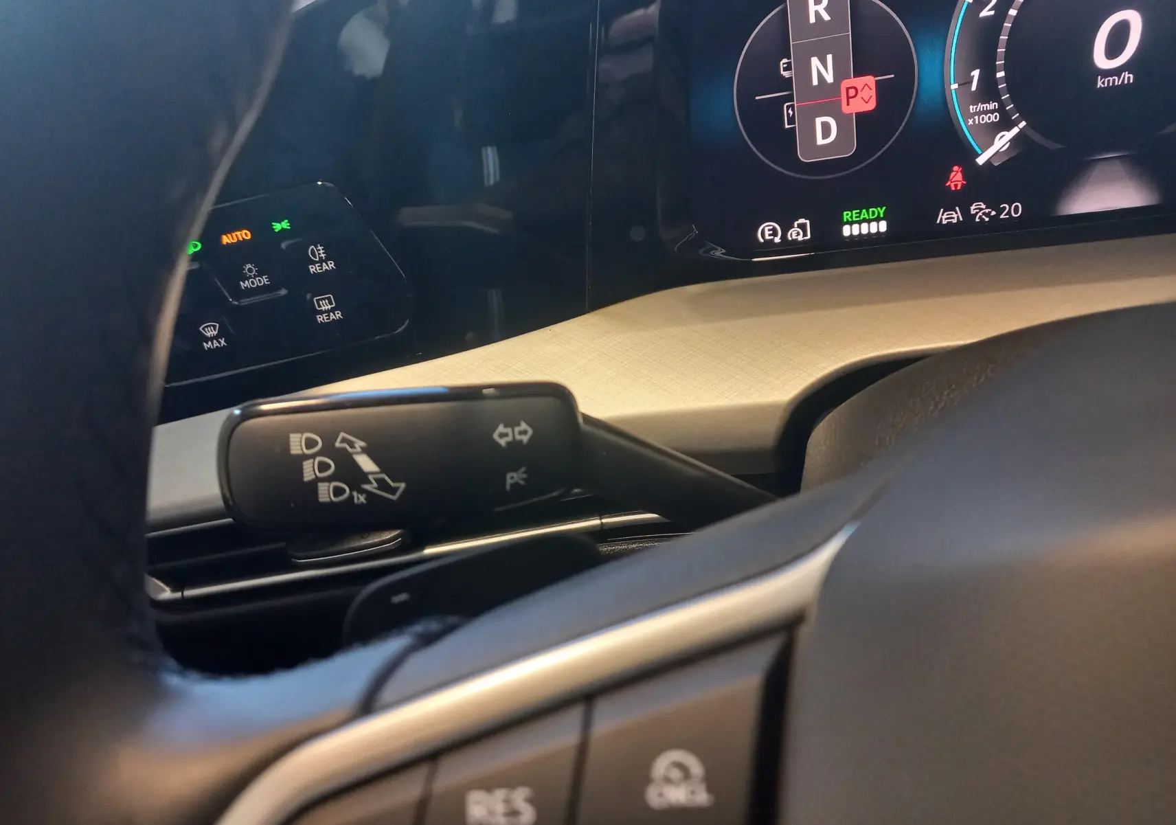 Vue rapprochée du combiné d'instruments et du commodo gauche d'une Volkswagen Golf 1.5 eHybrid 2025 avec tableau de bord beige.