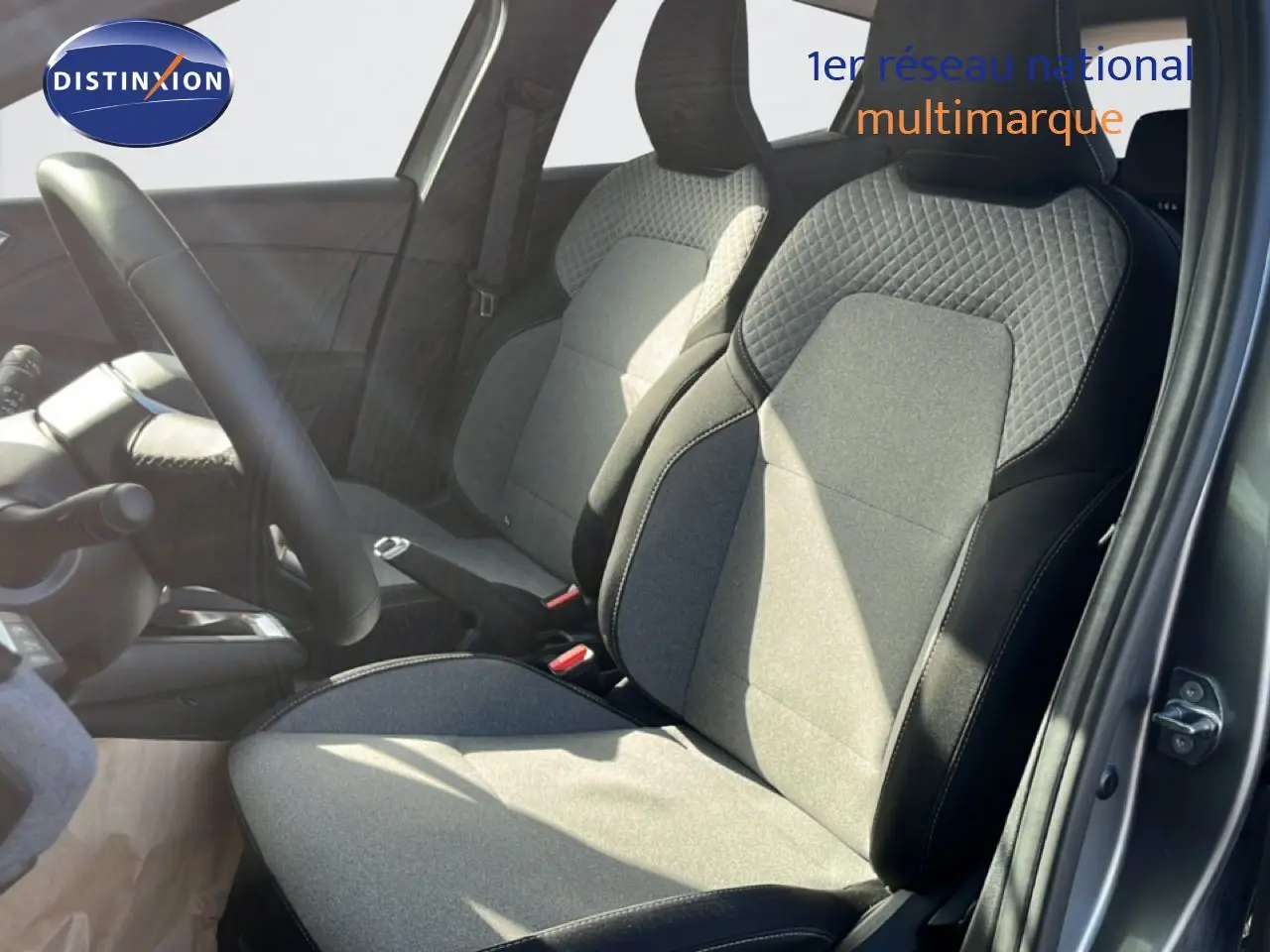 Vue intérieure côté conducteur de la Renault Clio 2025 gris schiste métal, sièges tissu noir et gris avec surpiqûres.